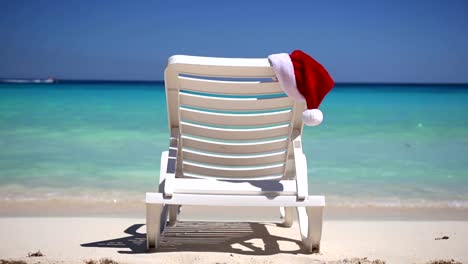 Sombrero-de-Santa-Claus-en-la-cama-solar-cerca-de-la-playa-tropical-calmo