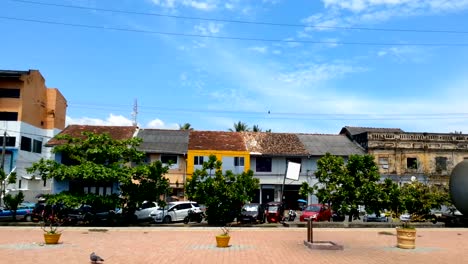 Viejas-casas-arruinadas,-tráfico,-gente-caminando-por-calle-suburbana