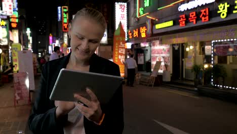 Frau-mit-Touch-Pad-auf-der-Straße-von-Seoul-in-der-Nacht,-Südkorea