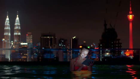 Mujer-con-almohadilla-en-piscina-en-la-azotea-de-noche-Kuala-Lumpur