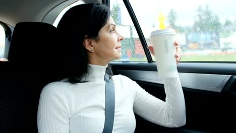 Woman-sitting-in-car-holding-disposable-cup