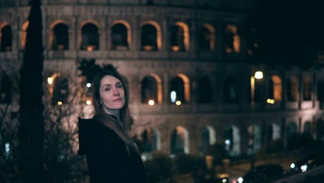 Portrait-of-young-brunette-woman-standing-near-Colosseum-in-Rome,-Italy-in-evening.-Girl-turns-and-looks-at-camera