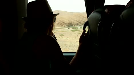 Young-woman-looking-trough-the-window-and-playing-with-hands-sitting-on-backseats-in-bus-during-road-trip