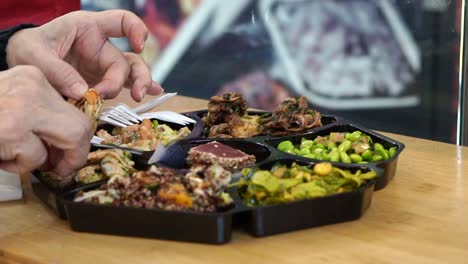 Hand-eating-cold-dish-seafood-and-salad-platter-in-Europe-open-market-shot-in-slow-motion-120-fps