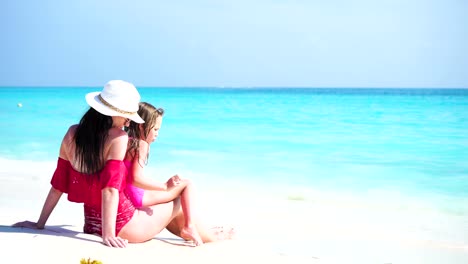 Little-adorable-girl-and-young-mother-at-tropical-beach-enjoy-their-sea-vacation