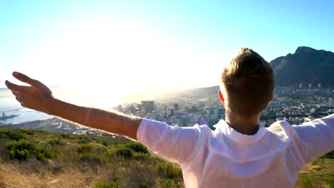 Freedom-in-nature,-man-arms-outstretched-at-sunset