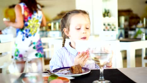 Adorable-kleines-Mädchen-mit-einem-Frühstück-im-Café-im-Freien