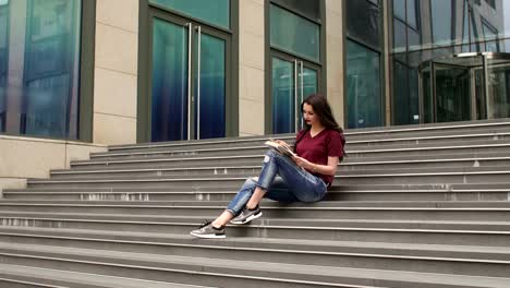 Joven-estudiante-leyendo-un-libro-sentado-en-los-escalones.