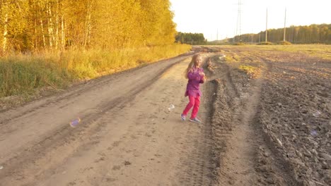 Happy-young-girl-blowing-soap-bubbles,-twisting-and-turning-around.-Outdoor-autumn.-Slow-motion