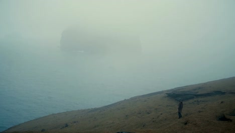 Junge-Frau-zu-Fuß-durch-das-Feld-am-Ufer-des-Meeres-und-denken,-die-Natur-Islands-erkunden