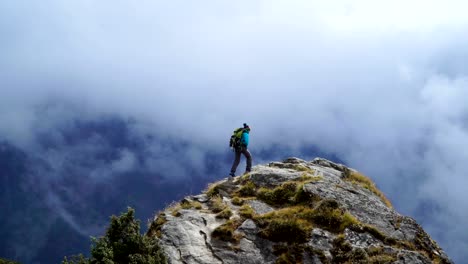 Girl-with-backpack-reaching-up-top-of-mountain-and-raised-hands