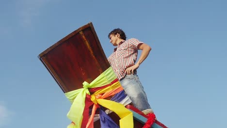 Unten-in-der-Ansicht-der-junge-Mann-steht-auf-einem-Holzboot-Nase-nimmt-Selfie-mit-Handy-auf-den-blauen-Himmel-im-Hintergrund.-Slow-Motion.-1920-x-1080