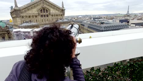 Tourists-looking-over-Paris-cityscape-with-Opera-Garnier-and-Eiffel-Tower-on-Lafayette-Gallery-terrace-with-coin-operated-binocular-telescope