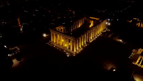 Video-de-noche-aérea-emblemática-antigua-colina-de-la-Acrópolis-y-el-Partenón-por-la-noche,-el-centro-histórico-de-Atenas