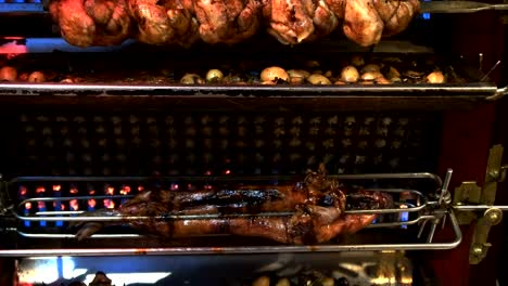 tilt-up-shot-of-a-pig,-chickens-and-vegetables-on-a-restaurant-rotisserie,-paris