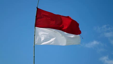 Die-Flagge-von-Indonesien-entwickelt-Wind-vor-dem-Hintergrund-des-blauen-Himmels