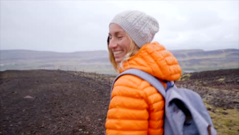 Slow-motion-Hiking-woman-gesturing-come-along-follow-me,-waving-and-hand-looking-at-camera,-Iceland