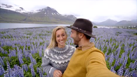 Slow-motion-video-of-young-couple-taking-selfie-portrait-in-purple-flower-field-in-Iceland-near-lake-and-mountains--Happy-people-travel-love-concept