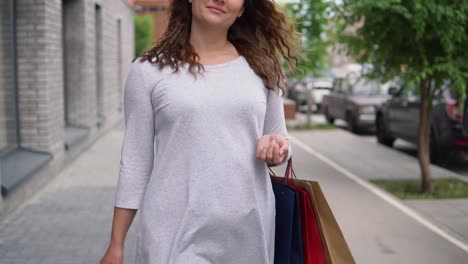 Una-hermosa-muchacha-es-caminando-por-la-calle-de-la-ciudad-después-de-comprar.-4K