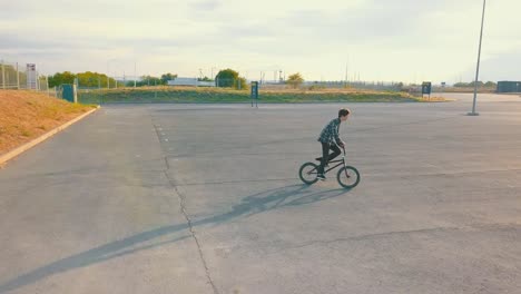 vista-del-joven-jinete-haciendo-piruetas-en-bicicleta-bmx-en-la-calle-urbanita-en-superficie-de-asfalto-de-vuelo