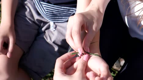 Mamá-pone-en-mano-de-su-hijo-teje-trenza-de-hojas.