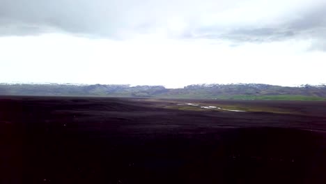 Drone-Ansicht-Antenne-des-jungen-Mannes-steht-auf-Flugzeug-stürzte-am-schwarzen-Sandstrand,-schaut-sich-um-ihre-Betrachtung-Umgebung-Sehenswürdigkeit-zu-besuchen-in-Island-und-stellen-mit-dem-Wrack---4K-Auflösung-ausgestreckte-Armen
