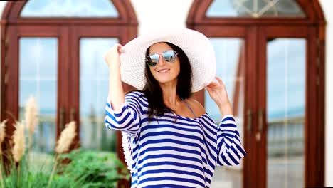 Beautiful-female-tourist-in-hat-sunglasses-and-striped-dress-having-fun-and-posing