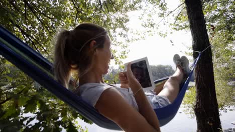 Young-woman-using-digital-tablet-on-hammock