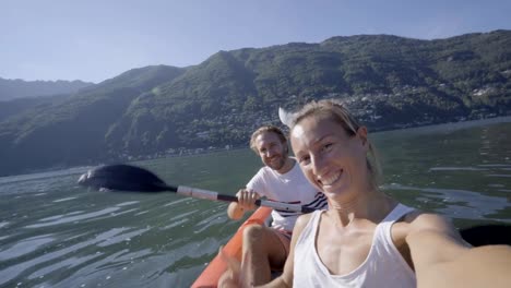 Joven-pareja-en-vacaciones-de-verano-disfrutando-de-canoa-en-el-lago-en-las-montañas.-Gente-de-viaje-divertido-concepto-de-vacaciones.-Tecnología-y-juventud-cultura-selfie---4K