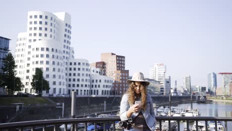 Frau-mit-Smartphone-auf-Brücke-über-dem-Fluss