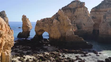 Ponta-da-Piedade,-lugar-famoso-en-el-sur-de-Portugal,-la-ciudad-de-lagos,-la-costa-rocosa,-olas-de-océano-Atlántico,-rocas-afiladas,-agua-azul,-flores-amarillas,-arco,-nadie,-playa-salvaje