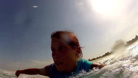 Surfer-girl-jumps-on-surf-and-starts-paddling