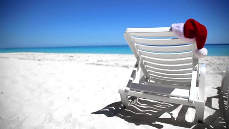 Santa-Claus-Hat-on-sunbed-near--tropical-calm-beach