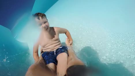 Happy-young-boy-going-down-curved-waterslide-in-slow-motion