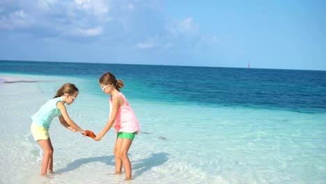 Entzückende-kleine-Mädchen-mit-Seesternen-auf-weißen-leeren-Strand