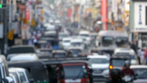 Blurred-unrecognizable-people-are-walking-around-city-center.-Cars-drive-on-roads-in-the-town.-Out-of-focus-is-backdrop-of-bustling-big-city-with-busy-traffic