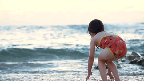 Kleine-Mädchen-spielen-am-Strand-im-Wasser-während-Sonnenuntergang-Stunde