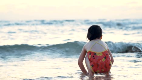 Niña-jugando-en-la-playa-en-el-agua-durante-la-hora-del-atardecer