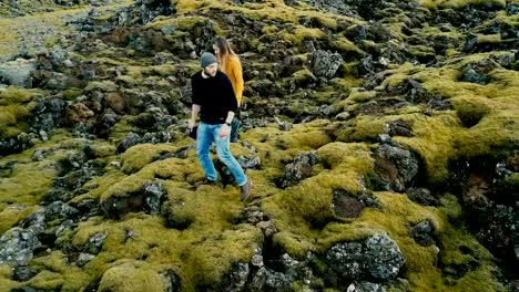 Aerial-view-of-young-stylish-couple-walking-through-the-volcanic-lava-field-in-Iceland.-Man-and-woman-go-to-their-car