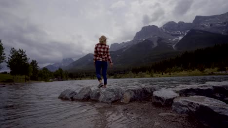 Young-woman-jumps-rock-to-rock-on-mountain-lake