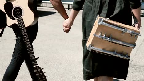 Young-beautiful-couple-walking-in-downtown-together,-Chicago,-America.-Man-holding-guitar,-woman-sketchbox