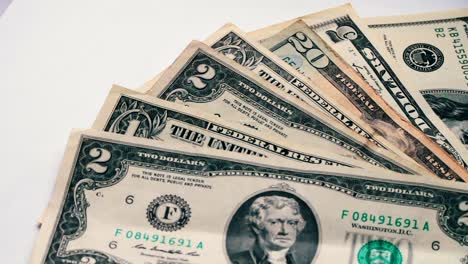 Woman-countslot-of-small-dollar-bills-on-the-table-with-a-white-background-macro-close-up