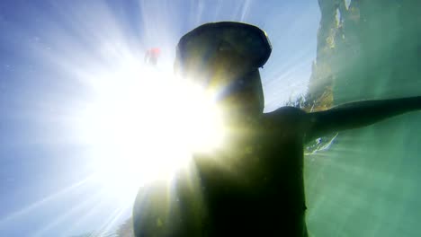 Young-man-snorkeling-with-sunrays-view-from-bellow,-uhd-shoot