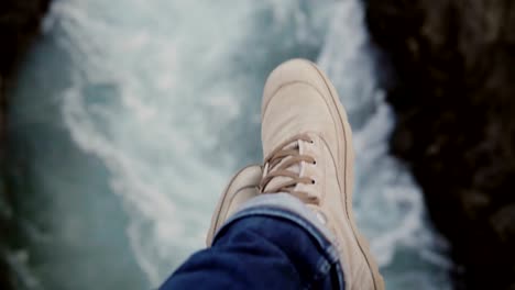 Close-up-view-of-male-foot-over-the-turbulent-stream-of-water-flowing-through-the-rocks,-mountains-river