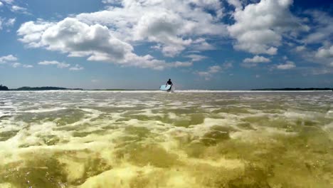 Imágenes-de-4K-de-un-surfista-corriendo-hacia-el-mar-con-una-tabla