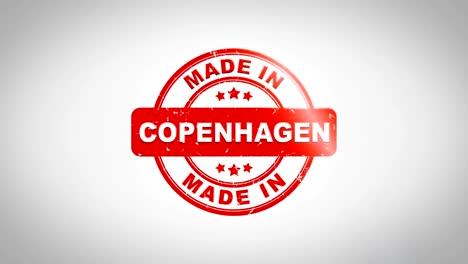 Hergestellt-In-Kopenhagen-unterzeichnet,-Stanz-hölzernen-Stempel-Textanimation.-Roter-Tinte-auf-Clean-White-Paper-Oberfläche-Hintergrund-mit-grünen-matten-Hintergrund-enthalten.