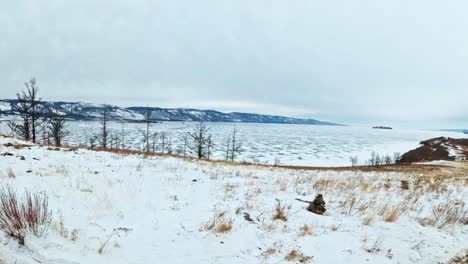 Travel-of-woman-on-ice-of-Lake-Baikal.-Pov-view.-Close-unique-buddhist-stupa-burkhan-monument-symbol-mystical-historic-ritual-island-Ogoi-landscape-mountains-shamanic-worship.-Trip-to-winter-island.