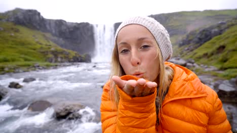 Portrait-of-blond-hair-woman-front-of-magnificent-waterfall-in-Iceland