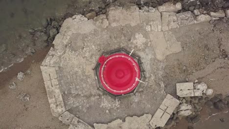 Drone-view-top-of-red-roof-of-sea-lighthouse-on-edge-seaside