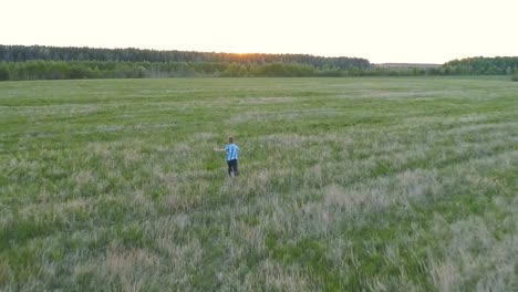 Junge-läuft-über-das-Feld-auf-Sonnenuntergang.-Hinten-Sie-Ansicht-von.